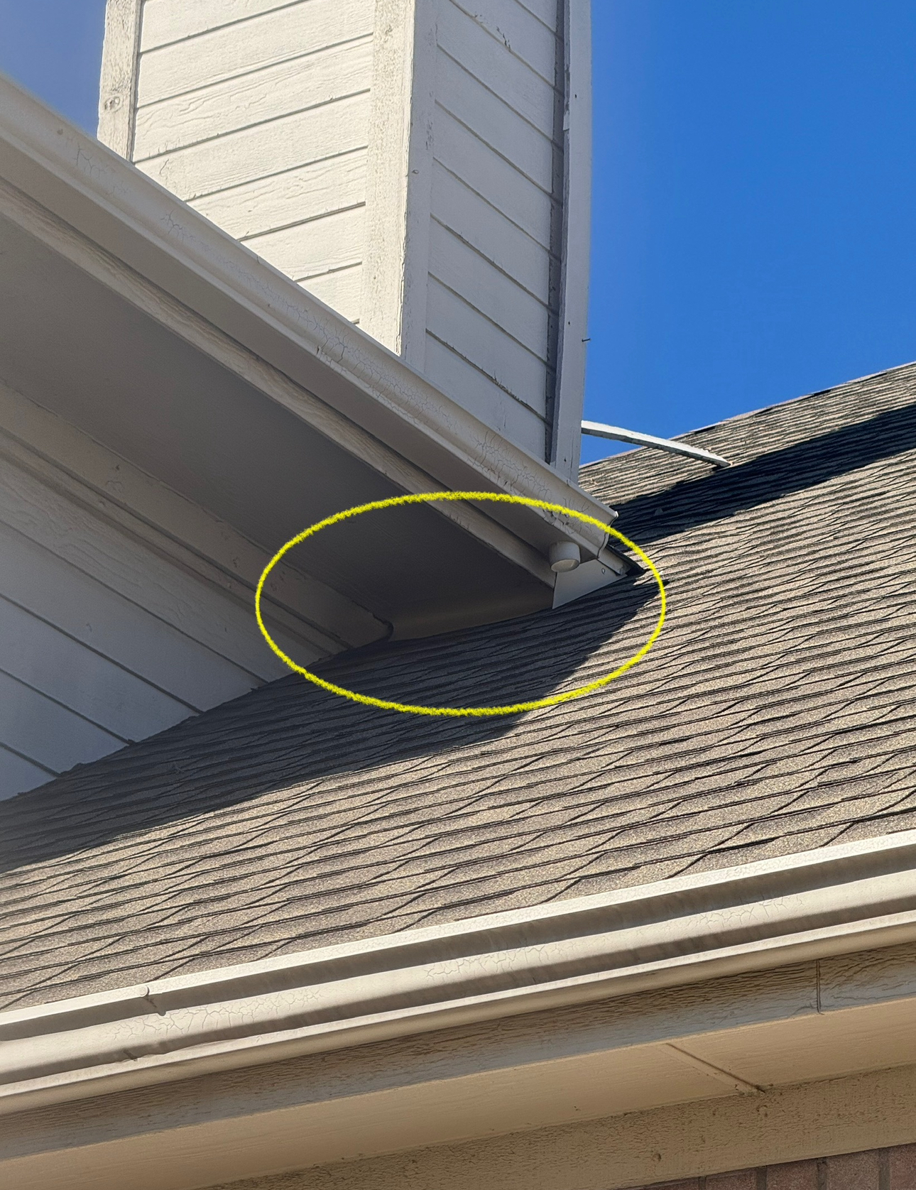 Gray roof and siding with a yellow circle highlighting a gap. Sunny, daytime.