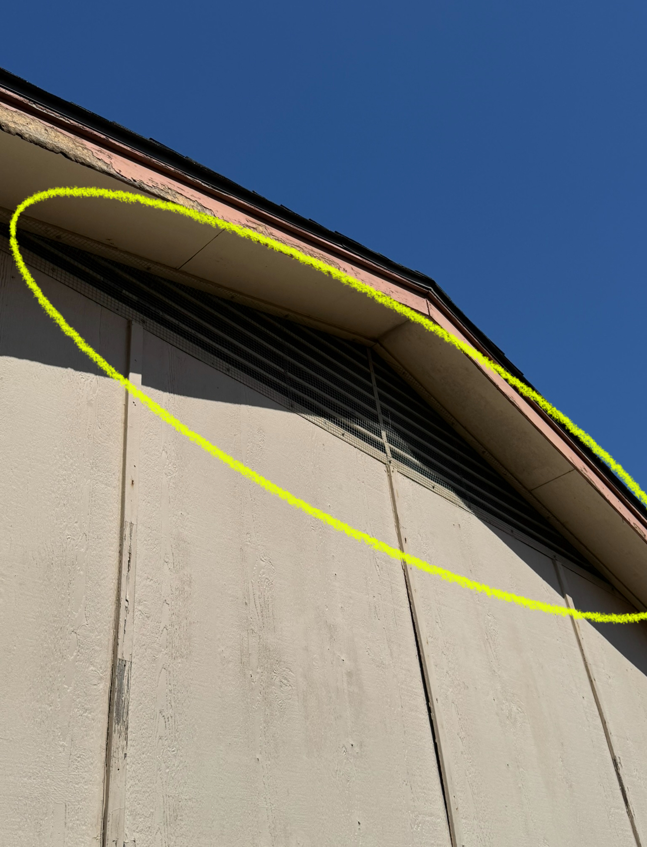 Yellow highlighted triangular roof with a vent against a clear blue sky.