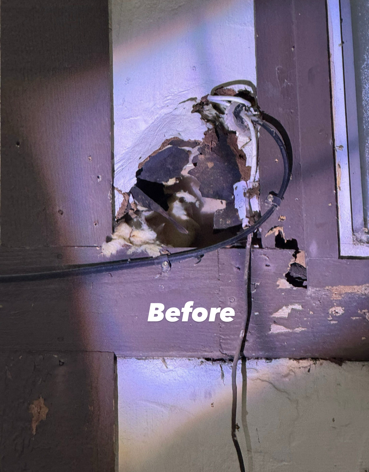 Damaged exterior wall around a cable entry point. Brown frame, white wall, and torn insulation. 