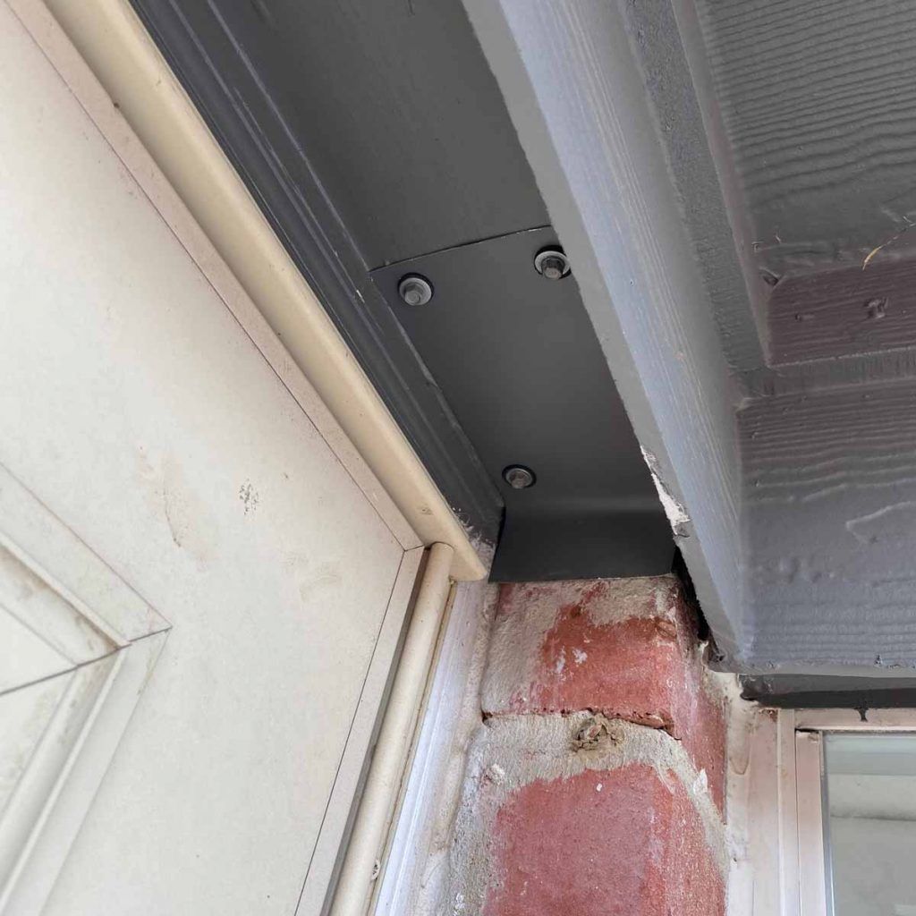 A brick wall with a white door and a black trim