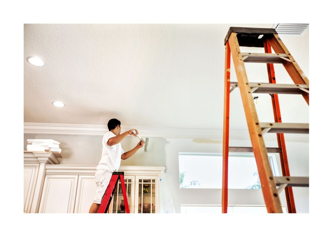 New Westminster Painting Employee on ladder painting on top of kitchen cabinets 