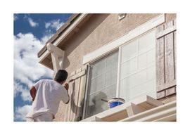 New West Painting employee painting outdoors on stucco wall