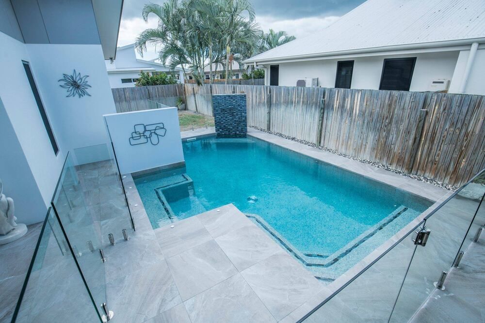 A Large Swimming Pool is in the Backyard of a House — Sun City Pools In Hyde Park, QLD