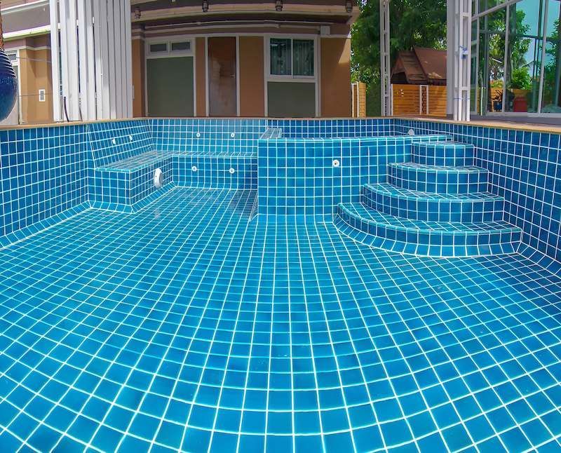 A Large Swimming Pool With Blue Tiles and Stairs — Sun City Pools In Hyde Park, QLD