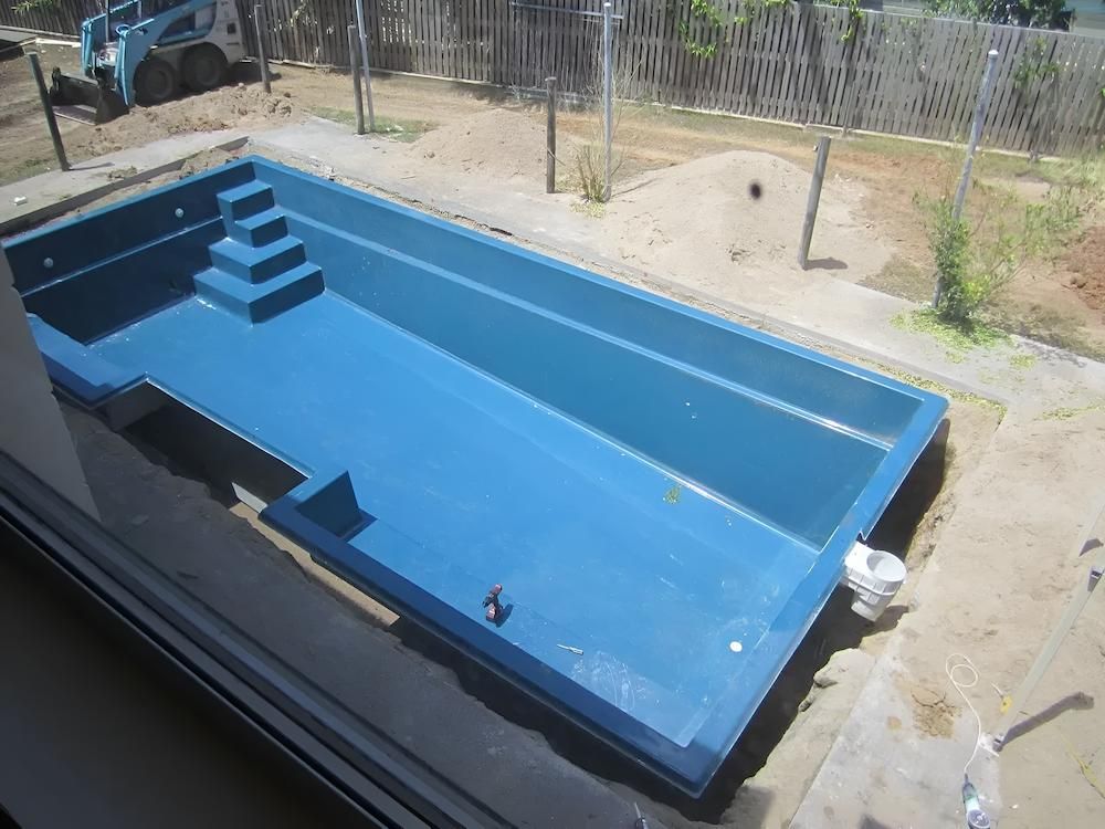 A Large Blue Swimming Pool With Stairs and a Bulldozer in the Background — Sun City Pools In Hyde Park, QLD