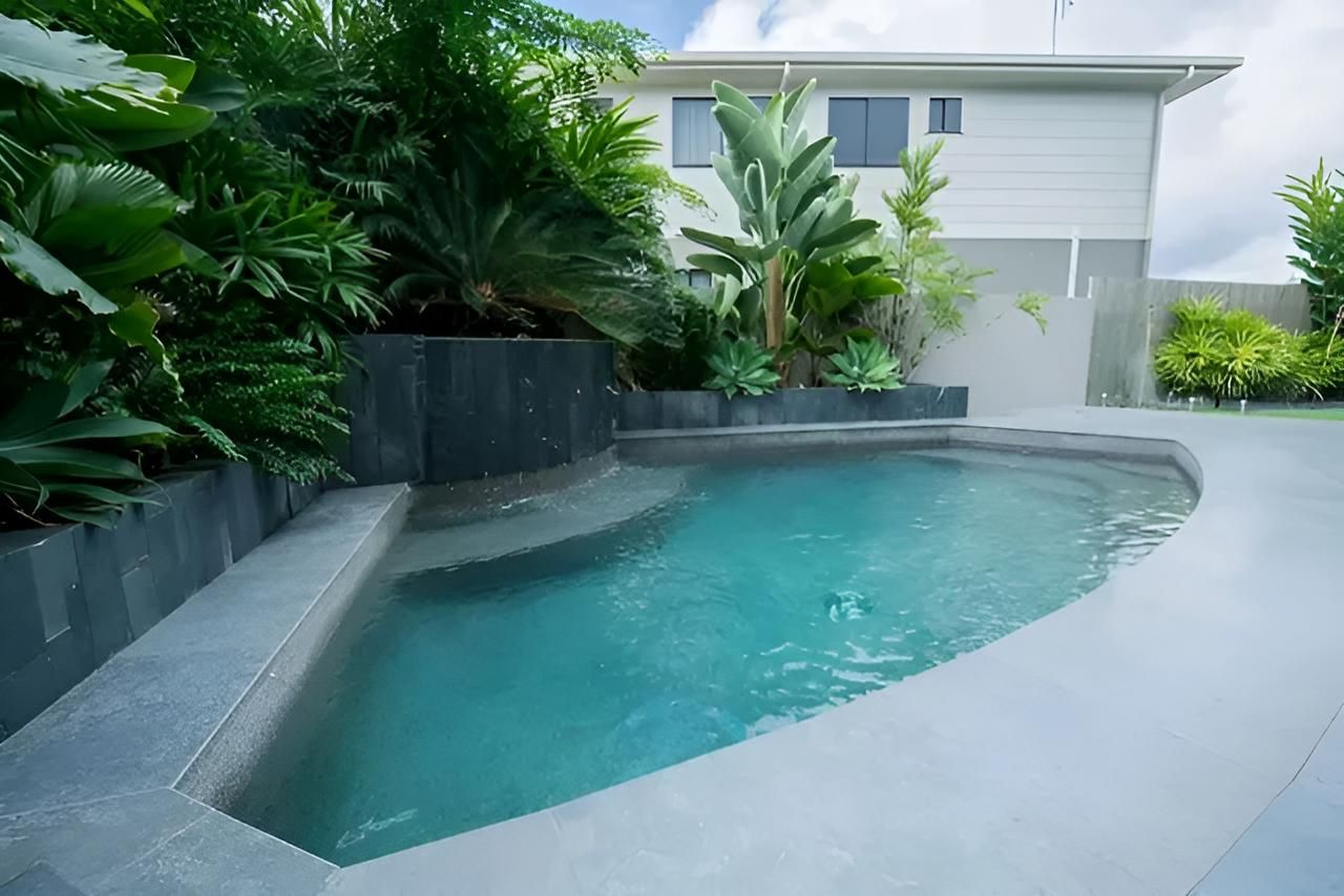 A Large Swimming Pool With a House in the Background — Sun City Pools In Hyde Park, QLD