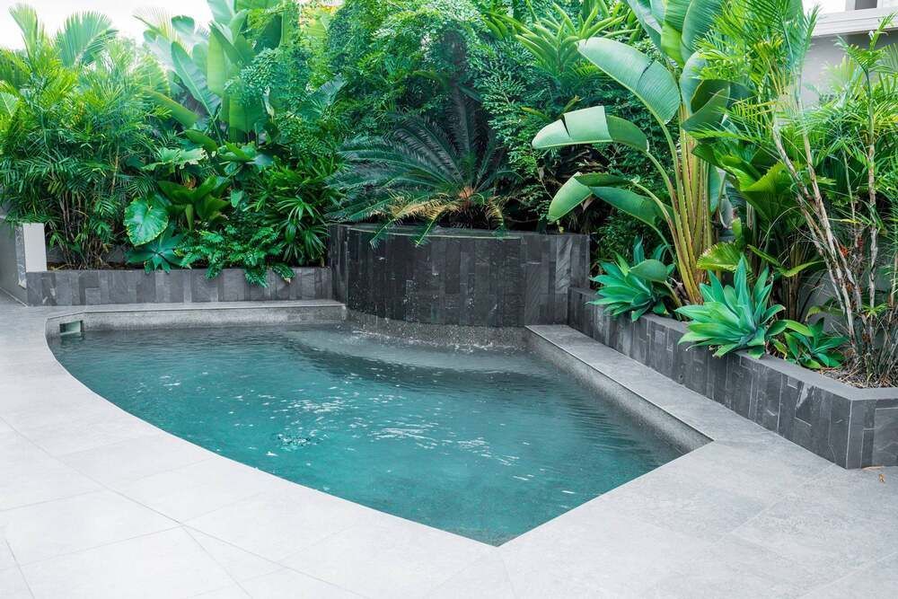 A Large Swimming Pool With a Blue Umbrella in the Backyard — Sun City Pools In Hyde Park, QLD