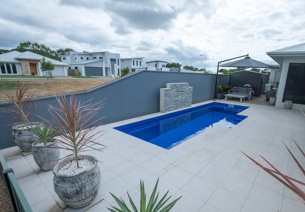 There is a Large Swimming Pool in the Backyard of a House — Sun City Pools In Hyde Park, QLD