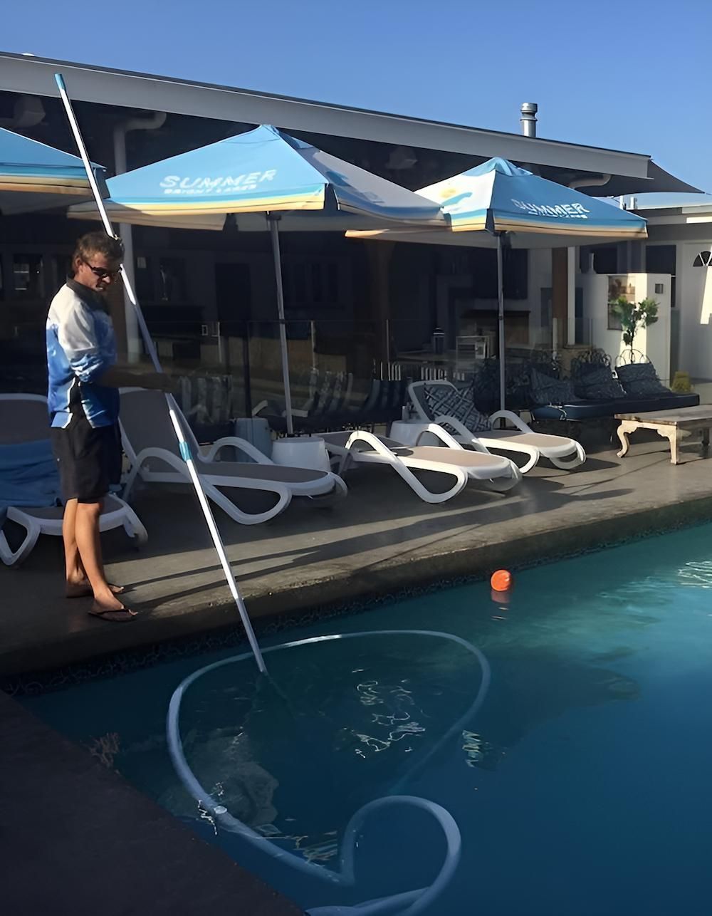 A Man is Cleaning a Swimming Pool With a Vacuum Cleaner — Sun City Pools In Hyde Park, QLD
