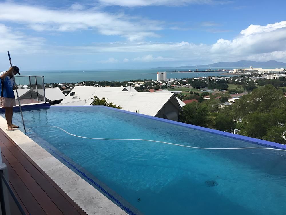 A Man is Standing on the Edge of an Infinity Pool Overlooking the Ocean — Sun City Pools In Hyde Park, QLD