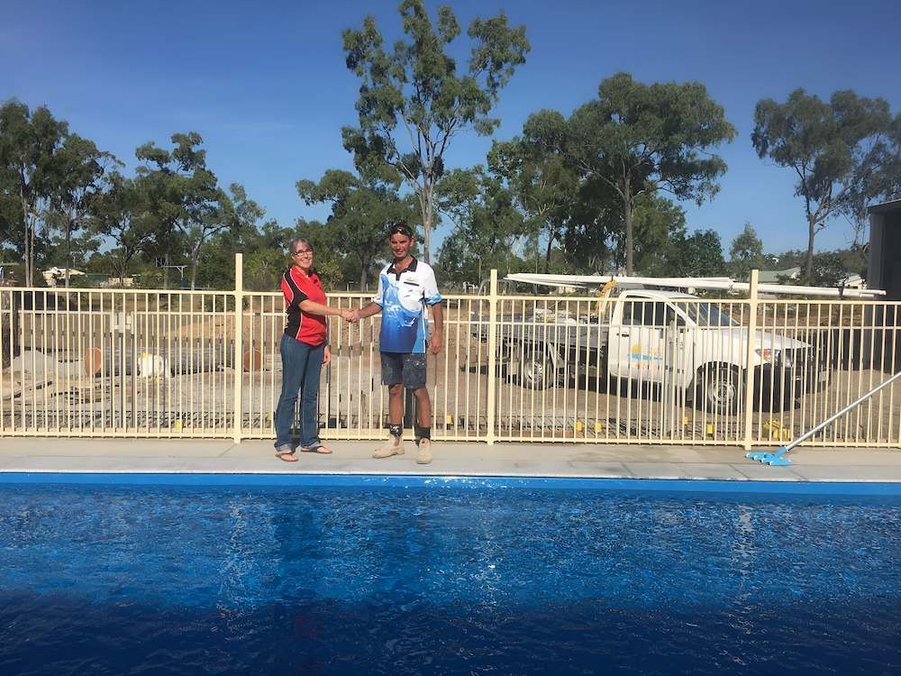 A Man and a Woman Are Standing Next to a Swimming Pool — Sun City Pools In Hyde Park, QLD