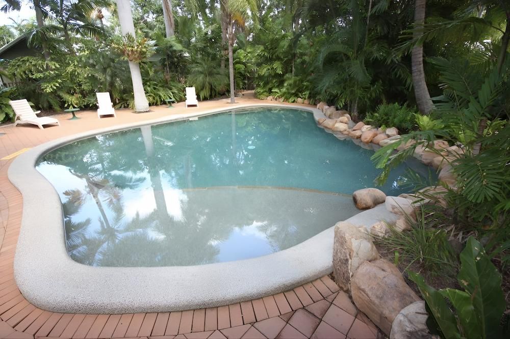 A Large Swimming Pool Surrounded by Trees and Rocks — Sun City Pools In Hyde Park, QLD