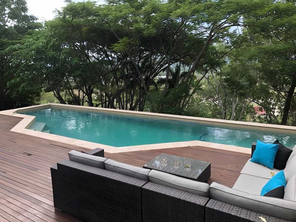 A Large Swimming Pool is Surrounded by Trees and a Wooden Deck — Sun City Pools In North Ward, QLD
