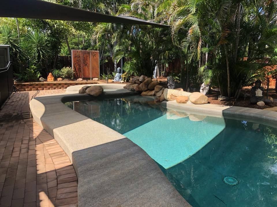 A Large Swimming Pool is Surrounded by Trees and a Brick Patio — Sun City Pools In Hyde Park, QLD