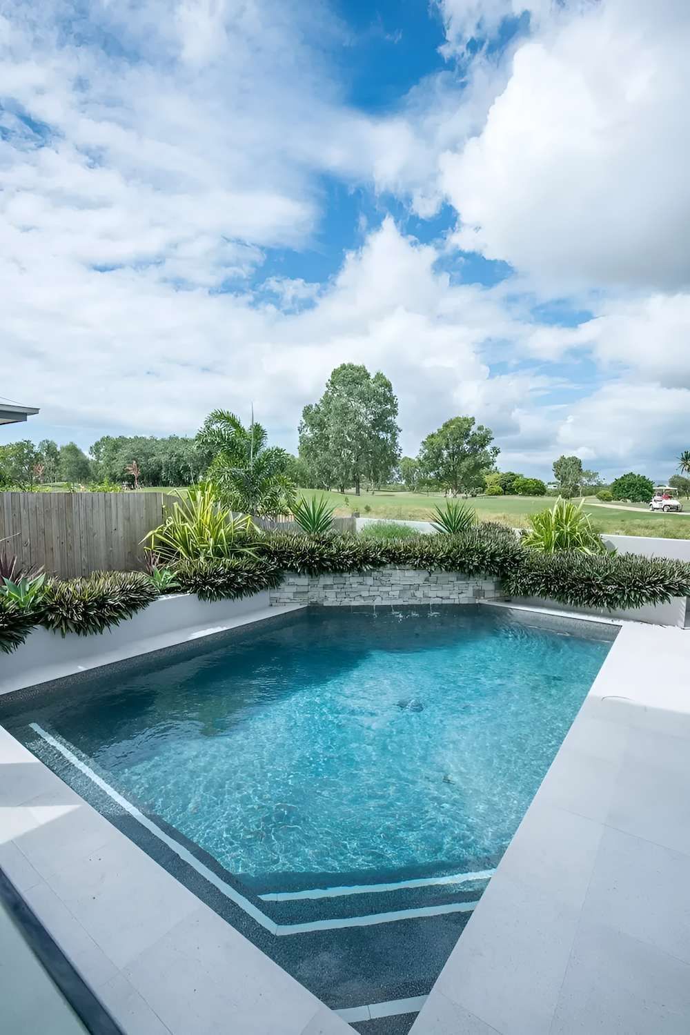 A Large Swimming Pool in the Backyard of a House With a Golf Course — Sun City Pools In Hyde Park, QLD