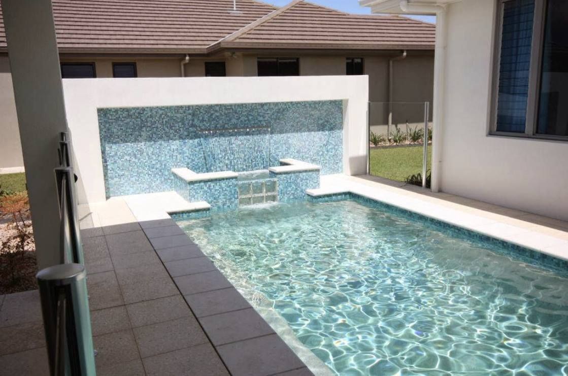 A Large Swimming Pool is in the Backyard of a House — Sun City Pools In Hyde Park, QLD