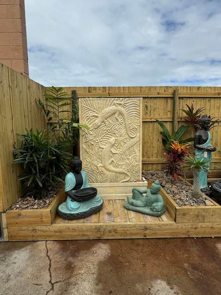 A Garden With a Fountain, Statues, Plants and a Wooden Fence — Sun City Pools In Hyde Park, QLD