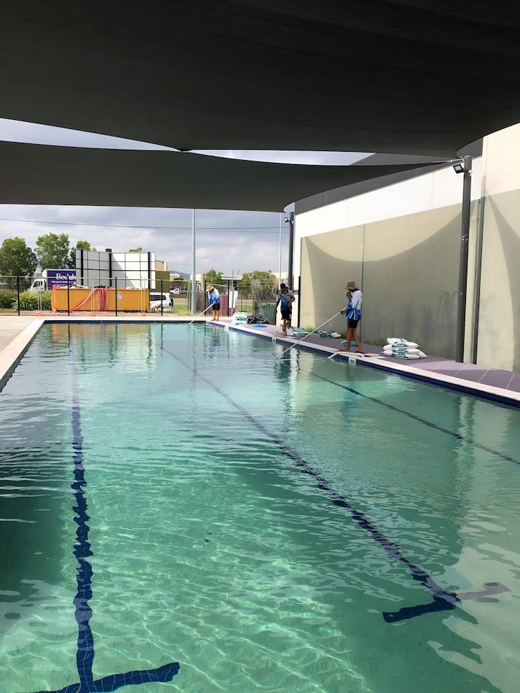 A Group of People Are Standing Around a Large Swimming Pool — Sun City Pools In Idalia, QLD