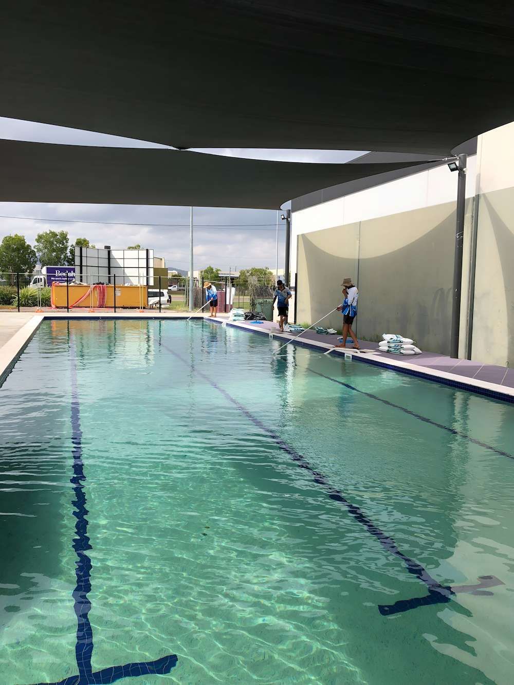 A Group of People Are Standing Around a Large Swimming Pool — Sun City Pools In Hyde Park, QLD