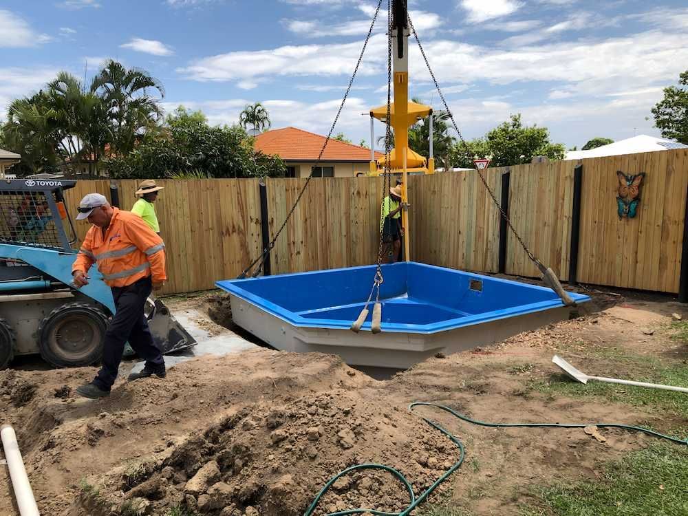 A Crane is Lifting a Blue Pool Into the Ground — Sun City Pools In North Ward, QLD
