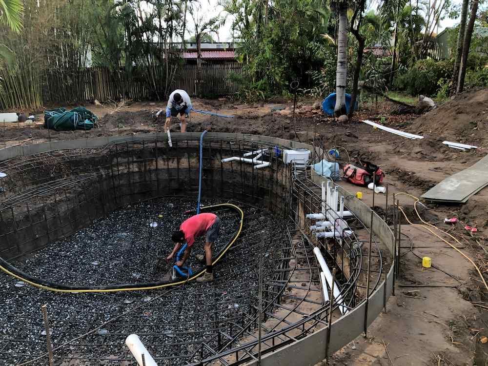A Man is Working on a Swimming Pool in a Backyard — Sun City Pools In Annandale, QLD