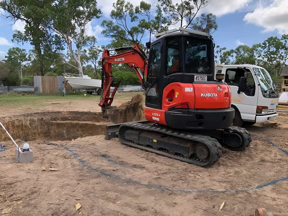 A Red Excavator is Digging a Hole in the Dirt Next to a White Truck — Sun City Pools In Ingham, QLD