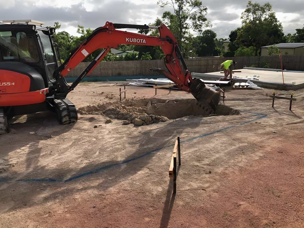 A Red and Black Excavator is Digging a Hole in the Ground — Sun City Pools In Magnetic Island, QLD