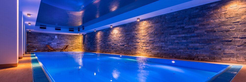 A Large Indoor Swimming Pool With Blue Lights on the Walls and Ceiling — Sun City Pools In Hyde Park, QLD