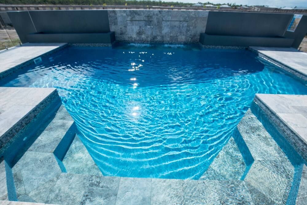 A Large Swimming Pool With a Waterfall in the Background — Sun City Pools In Hyde Park, QLD