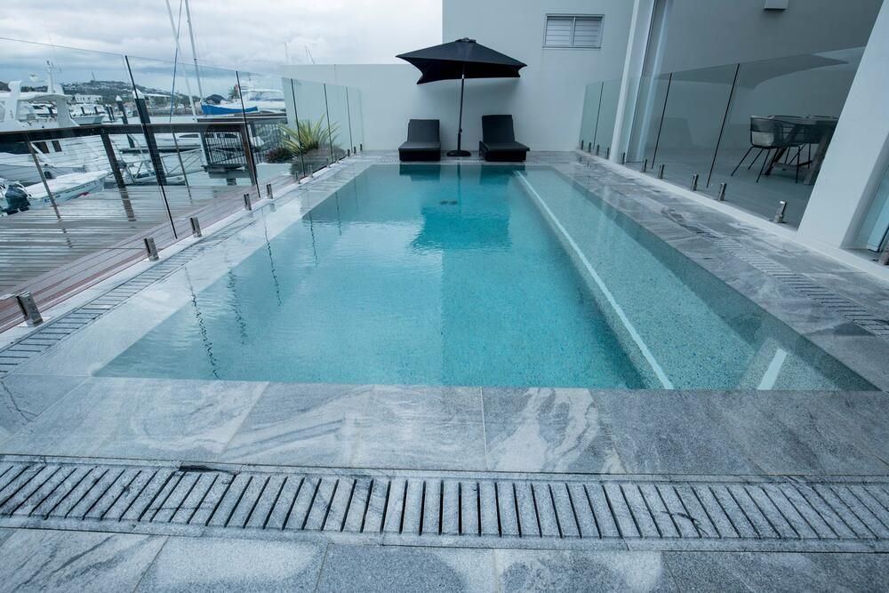 A Large Swimming Pool Surrounded by Chairs and Umbrellas — Sun City Pools In Hyde Park, QLD