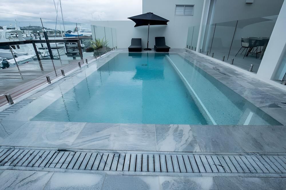 A Large Swimming Pool With a Black Umbrella in the Background — Sun City Pools In Bushland Beach, QLD