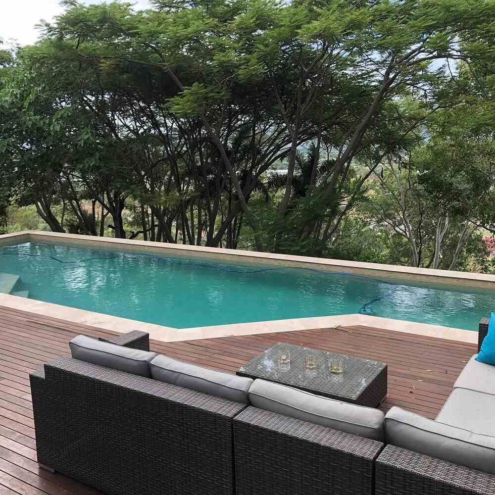 A Large Swimming Pool is Surrounded by Trees and a Wooden Deck — Sun City Pools In Hyde Park, QLD