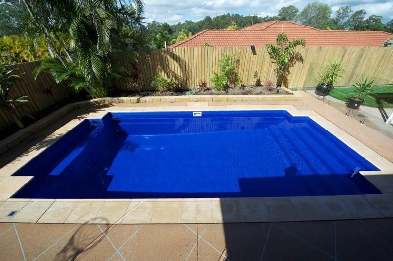 A Large Blue Swimming Pool With Stairs in Front of a House — Sun City Pools In Hyde Park, QLD