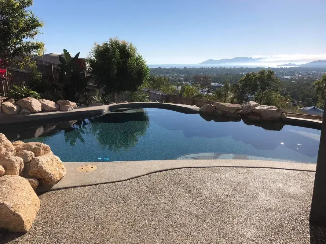 A Large Swimming Pool With a View of a City and Mountains — Sun City Pools In Hyde Park, QLD