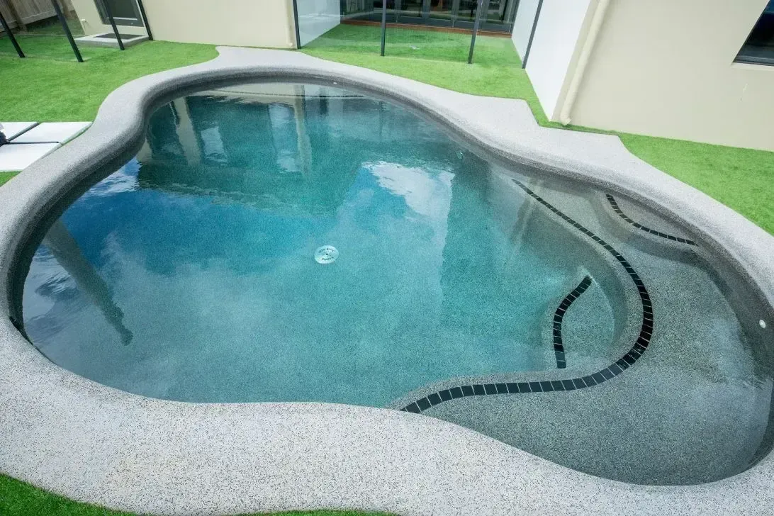 A Small Swimming Pool is Sitting on Top of a Lush Green Lawn — Sun City Pools In Hyde Park, QLD