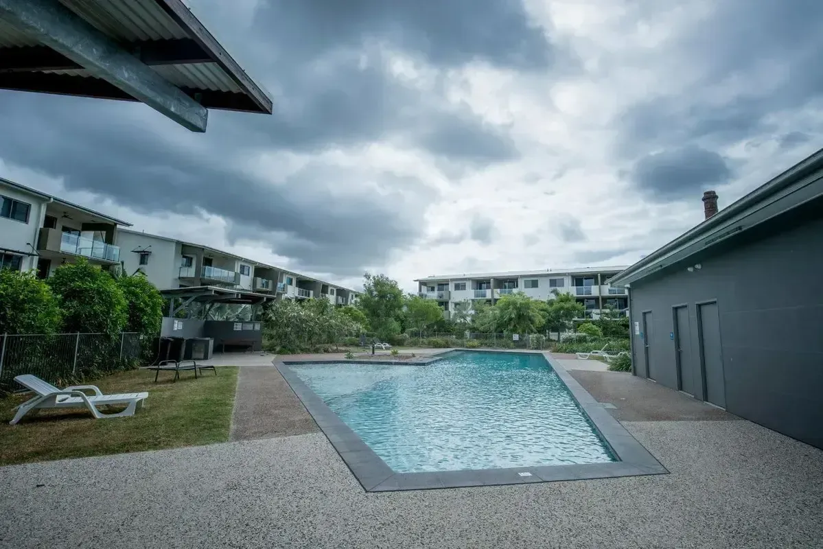 A Large Swimming Pool Surrounded by Buildings on a Cloudy Day — Sun City Pools In Hyde Park, QLD