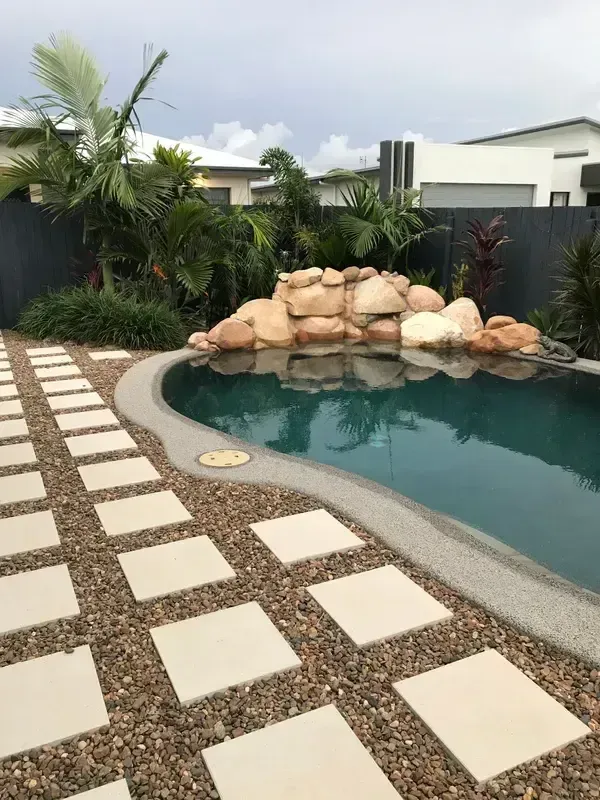 A Large Swimming Pool is Surrounded by a Fence and Trees — Sun City Pools In Hyde Park, QLD