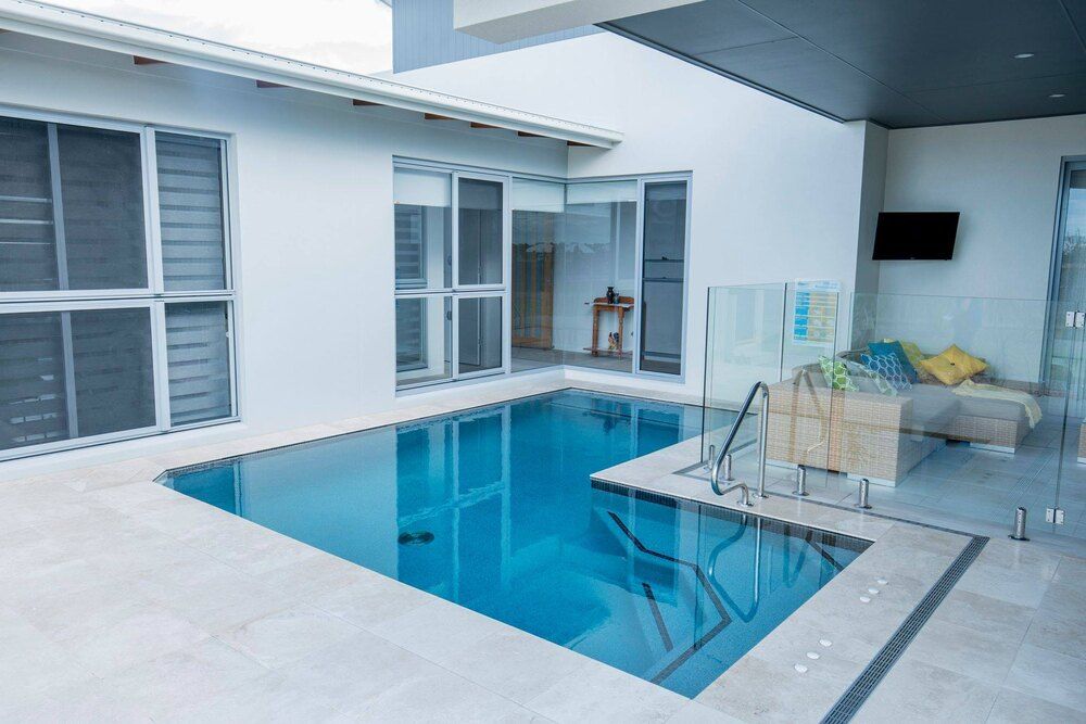 A Swimming Pool Surrounded by Palm Trees and Tiles — Sun City Pools In Hyde Park, QLD