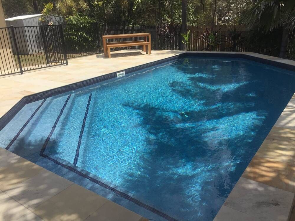 A Large Swimming Pool With a Picnic Table in the Background — Sun City Pools In Hyde Park, QLD