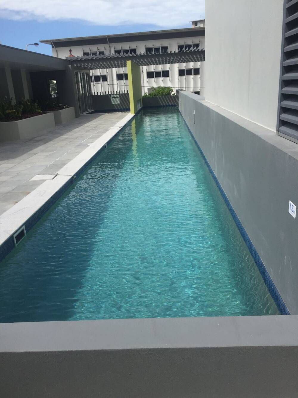 A Very Long Swimming Pool With a Building in the Background — Sun City Pools In Hyde Park, QLD