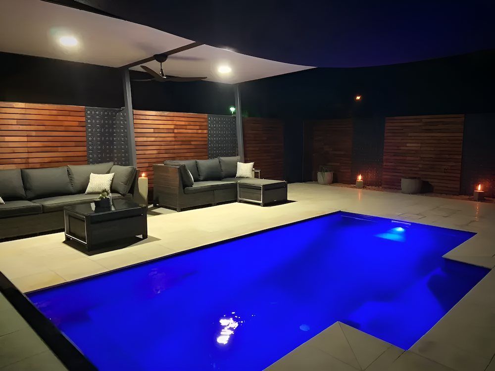 A Swimming Pool With a Couch and a Table in Front of It — Sun City Pools In Annandale, QLD