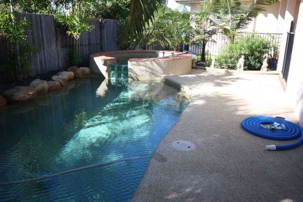 A Hose is Sitting Next to a Swimming Pool in a Backyard — Sun City Pools In Hyde Park, QLD