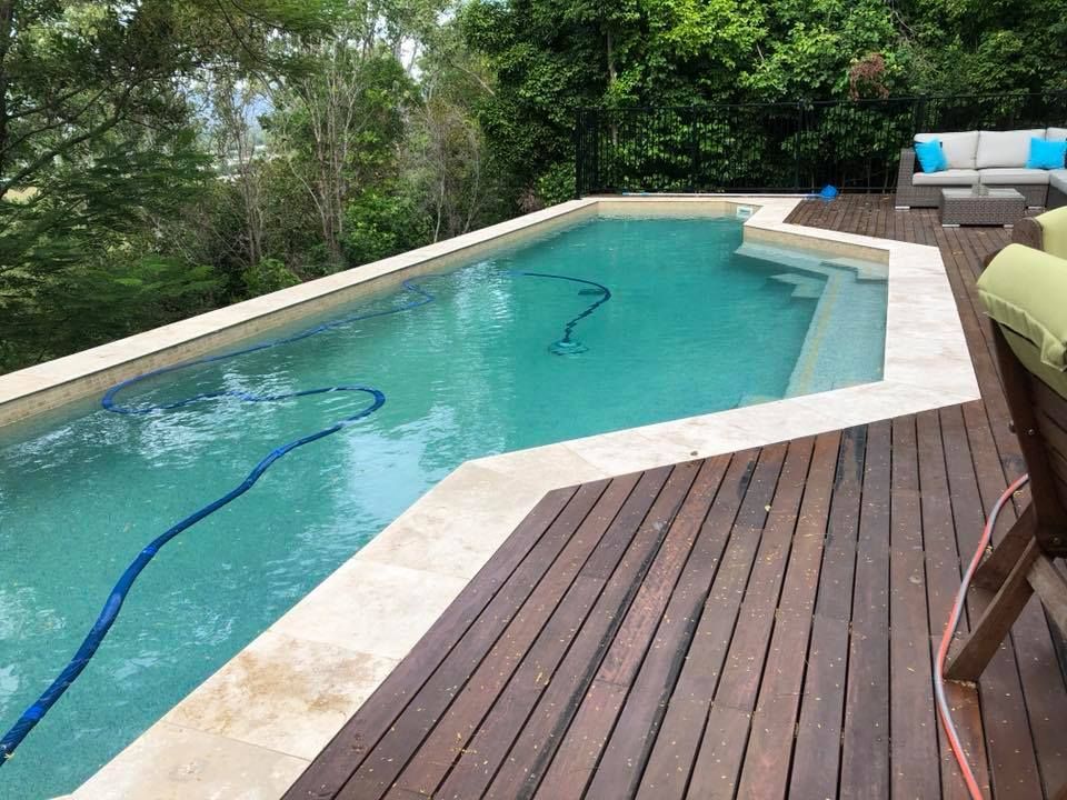A Large Swimming Pool is Surrounded by Trees and a Wooden Deck — Sun City Pools In Hyde Park, QLD