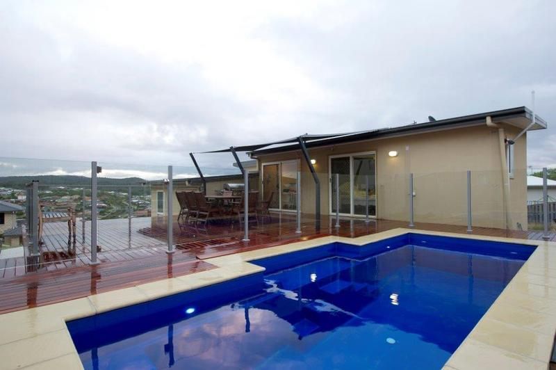 A House With a Large Swimming Pool in Front of It — Sun City Pools In Hyde Park, QLD