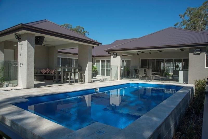 A Large Swimming Pool is in the Backyard of a House — Sun City Pools In Hyde Park, QLD