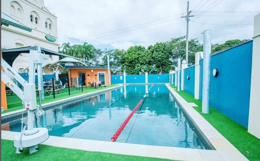 A Large Swimming Pool With a Red Lane and a Building — Sun City Pools In Hyde Park, QLD