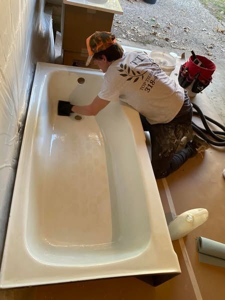 A man is cleaning a bathtub with a sponge.