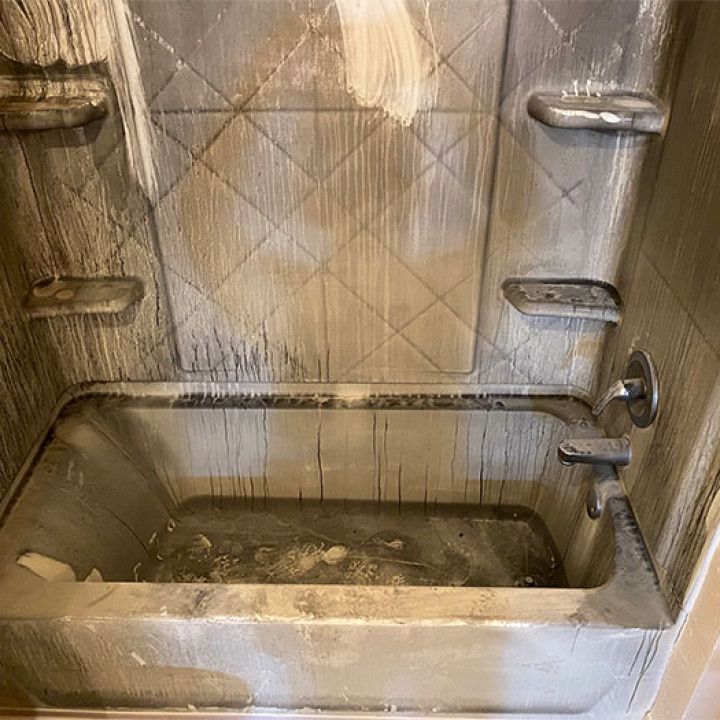 A dirty bathtub in a bathroom with a shower stall.