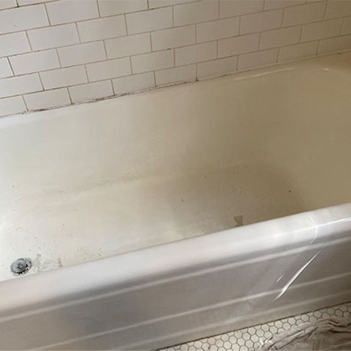 A white bathtub is sitting in a bathroom next to a white brick wall.