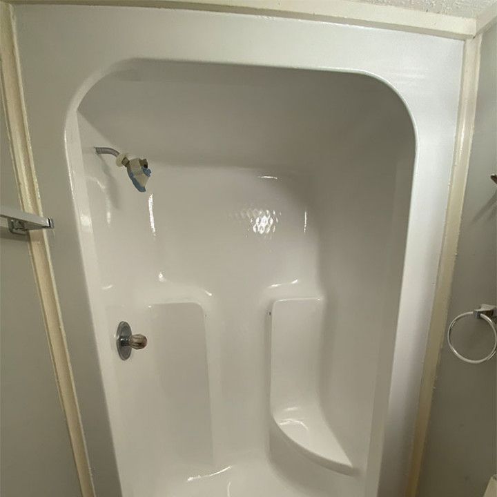 A white shower stall with a shower head in a bathroom.
